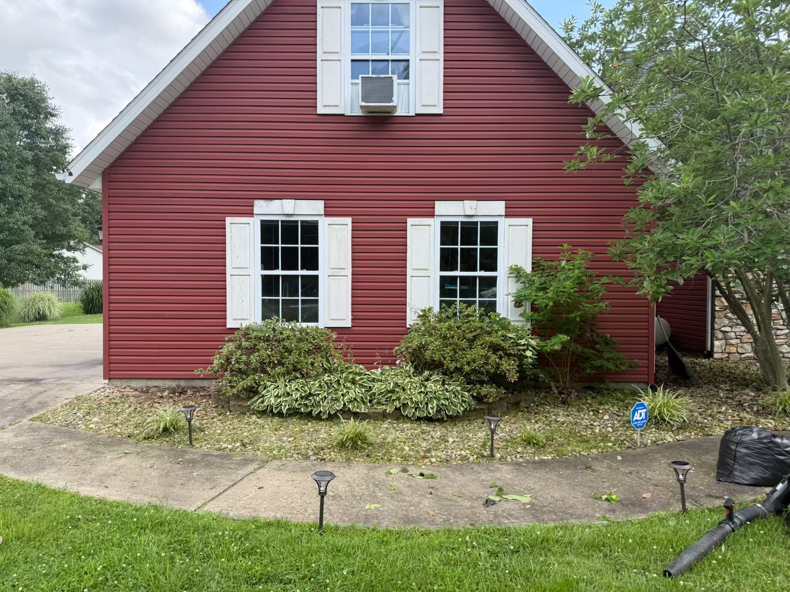 Red house exterior after vines removed and shrubs trimmed back — clean siding fully visible